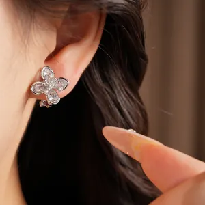 Macro detail of elegant silver clover flower ear clip with sparkling zircons on ear