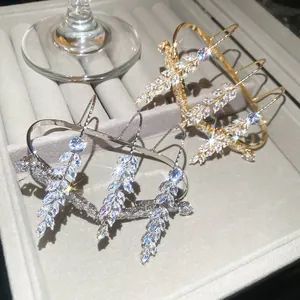 Detailansicht von funkelnden Zirkon-Ährenringen in Gold und Silber auf grauem Samttablett