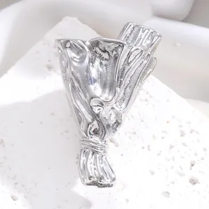 Detailansicht einer silbernen Blumenstrauß-Brosche auf weißem strukturiertem Stein.