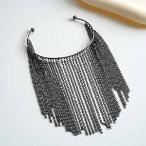 Detailopname van zwarte metalen cuff armband met lange ketting franjes
