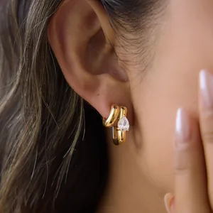 Close-up of 18k gold plated hoop earrings with pear-shaped cubic zirconia on model's ear