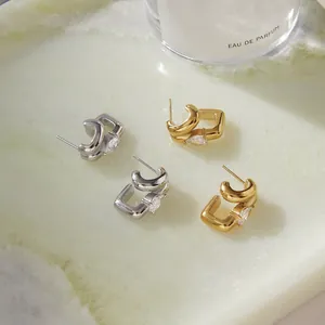 Detailed view of gold and silver geometric steel earrings with pear-cut zircon