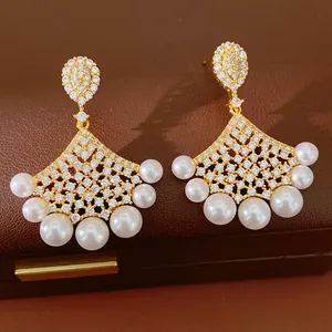 Detailed view of gold-plated fan-shaped earrings with pearls and sparkling zircons.
