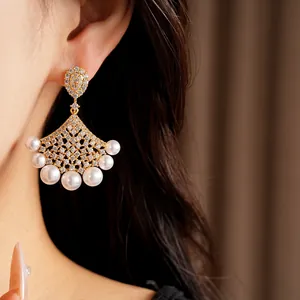 Close-up of elegant 18K gold-plated fan-shaped earrings with sparkling zircon and pearls.