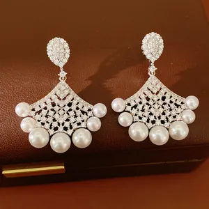 Close-up of elegant fan-shaped earrings with sparkling cubic zirconia and pearls.