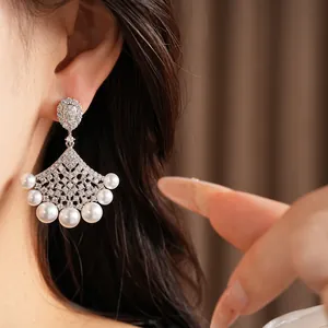 Close-up view of elegant fan-shaped earrings with zircon and white pearls on model