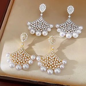 Detailed view of fan-shaped stud earrings featuring shimmering cubic zirconia and pearls.