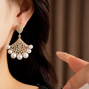Detailed macro view of elegant 18K gold fan-shaped earrings featuring pearls and zircons