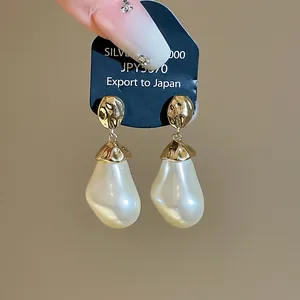 Nahaufnahme von Vintage-Ohrringen mit Barockperlen und gehämmerten Goldsteckern