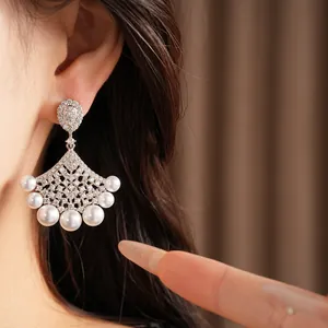 Elegant fan-shaped earrings with sparkling zircon and pearls shown in a close-up detail shot