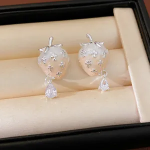 Close-up of sweet strawberry enamel earrings with silver crosses and sparkling zircon drops