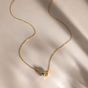Detail shot of an 18k gold-plated stainless steel necklace with a triple-ring pendant.