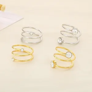 Close-up detail of golden and silver minimalist spiral stainless steel rings with zircons.