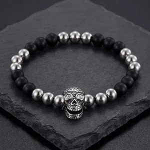 Retro skull charm bracelet with black agate beads and silver-tone accents on a stone background