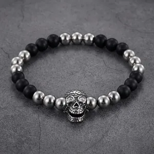 Macro detail of men's punk beaded bracelet featuring matte black stone and skull charm