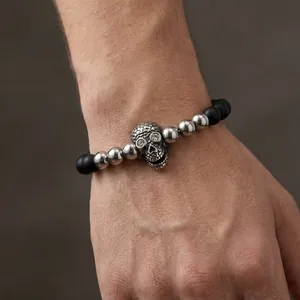 Close-up of men's beaded skull bracelet with matte black beads and zircon-inlaid eyes