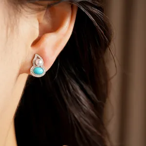 Detailed view of elegant silver gourd stud earrings with pearls and turquoise on a model's ear