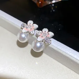 Close-up detail of elegant French-style camellia pearl stud earrings with sparkling zircon.