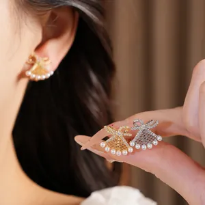 Detailed macro view of gold and silver bow fan-shaped earrings with elegant pearls