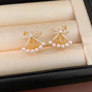 Detailed close-up of gold-plated fan-shaped bowknot clip-on earrings with small pearls