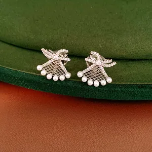 Close-up of silver-plated fan-shaped ear clips with bow and pearl details