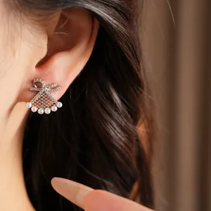 Close-up of bow-shaped fan pearl clip earring on ear showing the delicate design details.