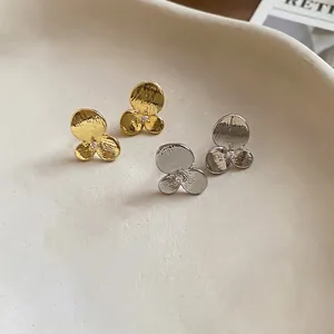 Boucles d'oreilles puces fleurs en zircon or et argent présentées sur un plateau chic