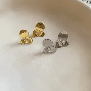 Vue macro de boucles d'oreilles fleurs or et argent avec zircons et tiges en argent