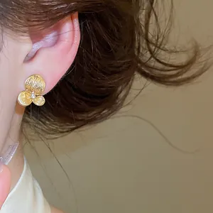 Gros plan d'une élégante boucle d'oreille fleur en or avec centre en zircon sur l'oreille.