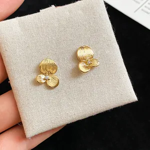 Gros plan détaillé de boucles d'oreilles fleurs dorées avec zircons sur tissu