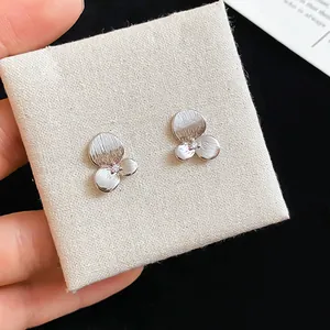 Vue détaillée de boucles d'oreilles en forme de fleur avec un zircon central.