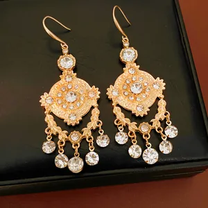 Gros plan détaillé de boucles d'oreilles vintage dorées évidées avec des strass étincelants.