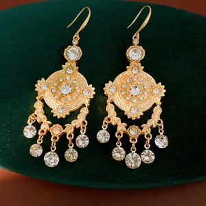 Vue détaillée de boucles d'oreilles style palais dorées avec cristaux sur velours
