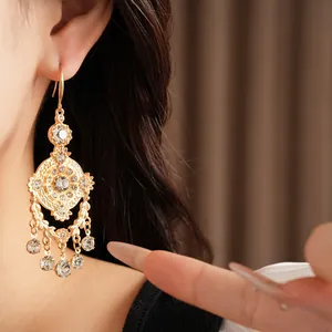 Gros plan d'élégantes boucles d'oreilles pendantes dorées avec cristaux