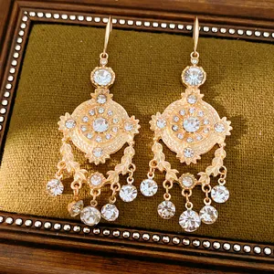 Gros plan de boucles d'oreilles dorées style palais avec motifs blé et strass