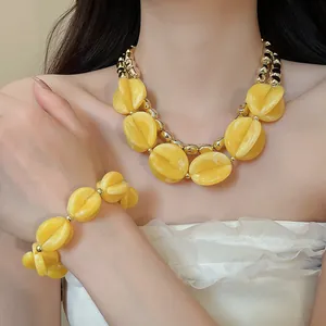 Primer plano de un conjunto de collar y pulsera de acrílico amarillo estilo bohemio
