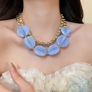 Primer plano de un collar de perlas ovaladas de acrílico azul mármol bohemio