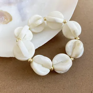 Vista detallada de una pulsera de cuentas de acrílico marmoleado blanco y oro.