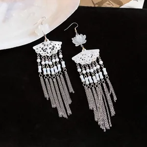 Detailed view of elegant fan-shaped earrings with long silver tassel and white flower charms.