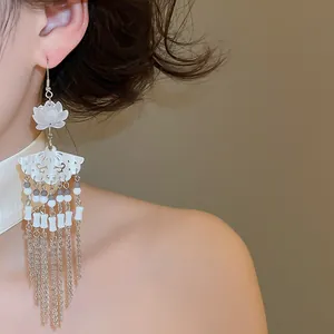 Detailed view of elegant Chinese style flower and fan earrings with long tassels on model