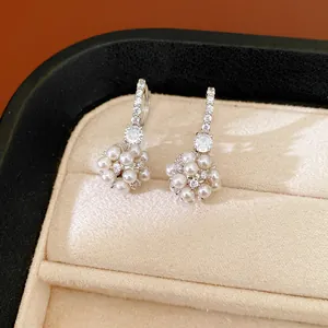 Close-up of elegant white pearl and zircon cluster drop earrings in a jewelry box