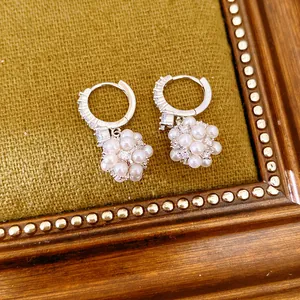 Elegant pearl flower ball hoop earrings featuring sparkling zircon accents on green fabric