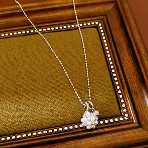 Detail showing a clustered pendant with white pearls and zircons on a silver bead chain.