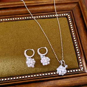 Detail view of silver-toned floral pearl necklace and earrings set on vintage frame