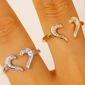 Macro view of gold and silver heart-shaped adjustable rings with sparkling zirconia inlay