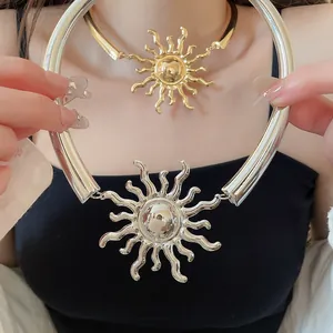 Dettaglio di una collana con ciondolo a sole in metallo in finiture oro e argento.