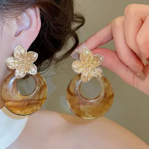 Vintage French style gold metal flower earrings with marbled brown resin hoops on model's ear