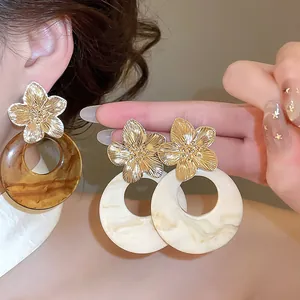 Macro view of vintage resin earrings showing the intricate metallic flower and marble texture