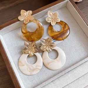 Detail view of French vintage earrings featuring gold metal flowers and resin marble hoops.