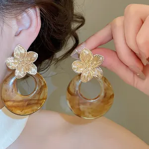 Detailed view of French retro gold flower stud earrings with brown marble resin hoop